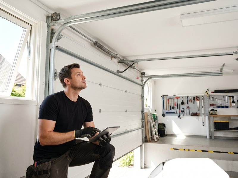 Technician inspecting a sectional garage door with a tablet