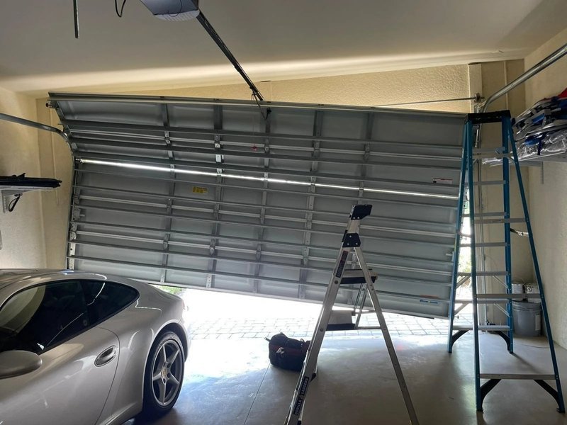 Garage door off its track hanging crooked inside a garage
